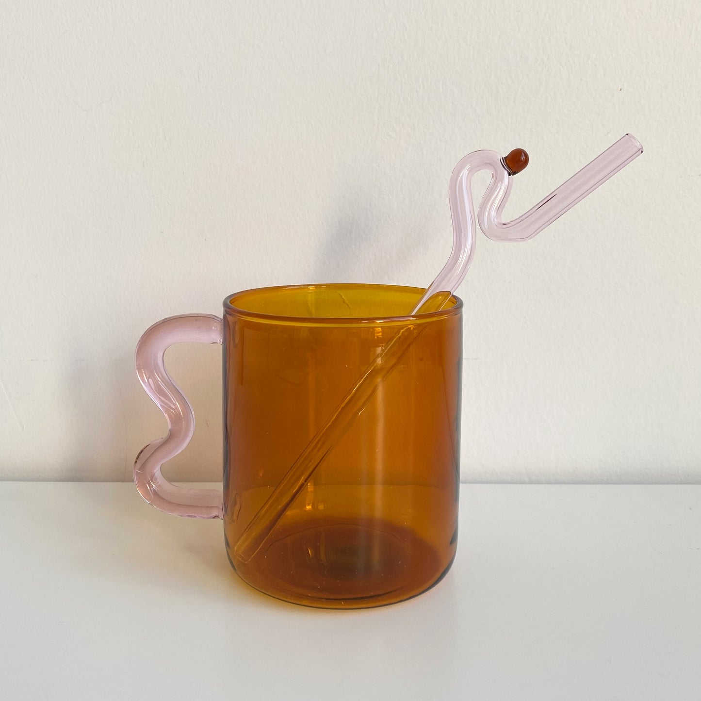 wave handle glass mug in amber with pink handle